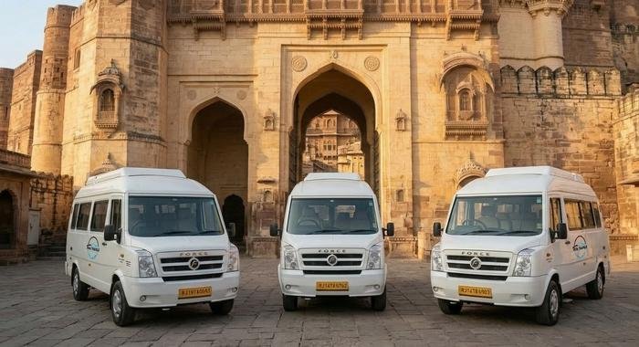 Three Ruia Travels tempo traveller vans parked outside a Jodhpur fort gate